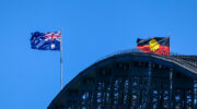 The Australian flag and Australian Aboriginal flag fly with a westerly wind on the Sydney Harbour Bridge on a Spring afternoon. This image was taken from Kirribilli on the eastern side of the bridge.
