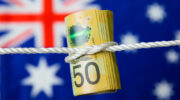 Wad of Australian fifty dollar notes tied in a knot on an Australian flag.