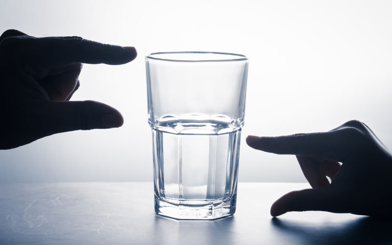 Glass half full water with hands measure in different position, mindset of positive thinking in crisis and opportunity concept