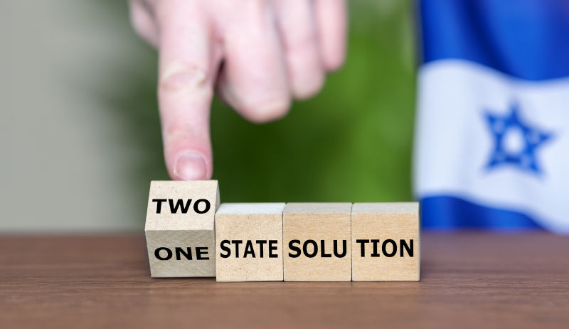 Hand turns cubes and changes the expression 'one state solution' to 'two state solution' next to an Israel flag, Symbol for an Israel and Palastine state.