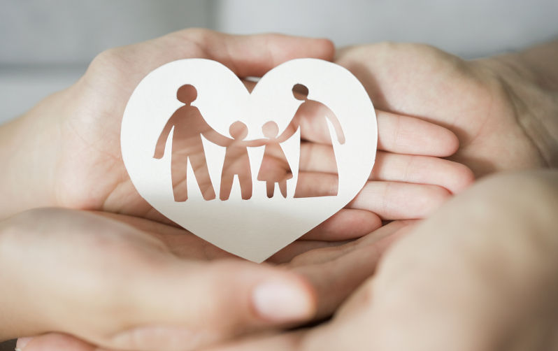 Hands holding paper family cutout, family home. Image: iStock / SewcreamStudio