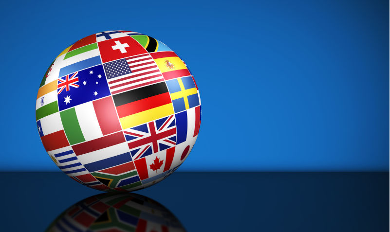 Globe and international flags of the world on blue background with copy space. Image: iStock / NiroDesign