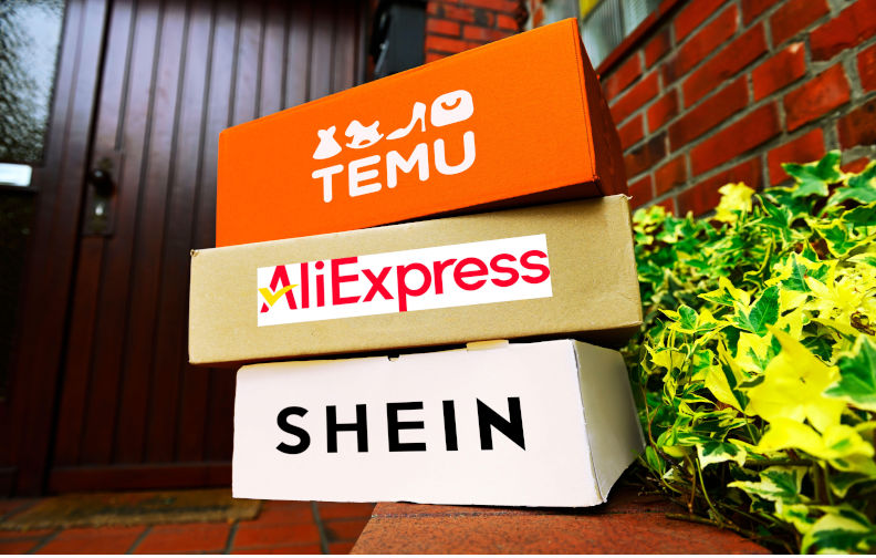 Stacked parcels from the Chinese mail order companies Temu, AliExpress and Shein in a building entrance, photomontage. Image: Alamy. Contributor: mauritius images GmbH Image ID: 3BNN9J2