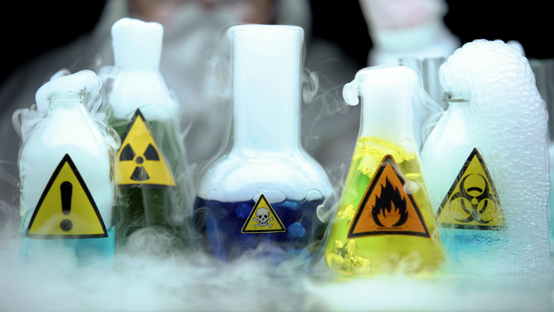 Marked dangerous liquids evaporating in flasks in front laboratory worker. Image: iStock / Motortion