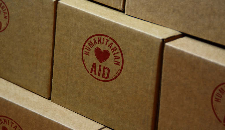 Humanitarian Aid stamp printed on cardboard box. Help refugees, volunteering and rescue during the crisis concept. Image:iStock/Arkadiusz Warguła