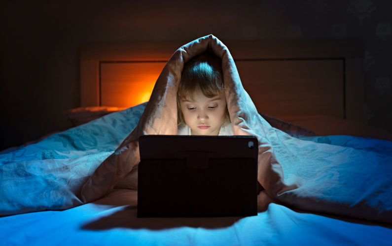 little girl tablet under blanket at night. Image: iStock / zahar2000
