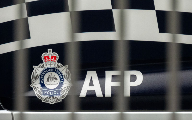 The side of a Australian Federal Police vehicle parked outside the Nigel Love Building at the international terminal of Sydney Kingsford Smith Airport. In the foreground are the metal bars of a pedestrian barrier on a road median strip. This image was taken on a hot and sunny afternoon approaching sunset on 9 November 2024. Image:iStock/The side of a Australian Federal Police vehicle parked outside the Nigel Love Building at the international terminal of Sydney Kingsford Smith Airport. In the foreground are the metal bars of a pedestrian barrier on a road median strip. This image was taken on a hot and sunny afternoon approaching sunset on 9 November 2024. Image: iStock/ SCM Jeans
