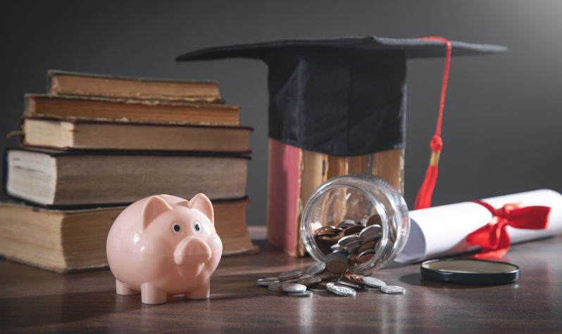 Graduation hat, book, diploma, coins and piggy bank on the wooden table. Image: iStock / Andranik Hakobyan
