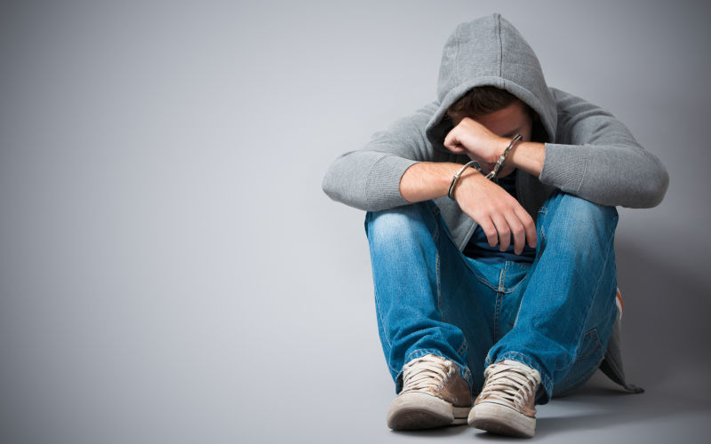 A teenager who has been arrested and handcuffed Image iStock credit AlexRaths