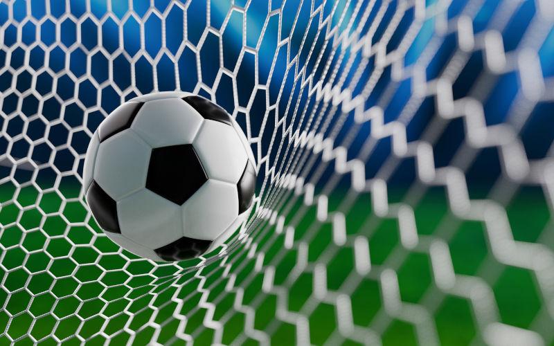 Closeup of a soccer ball in the goal net under stadium lights, representing scoring, success, and the thrill of a football game. Image iStock Credit Alones Creative