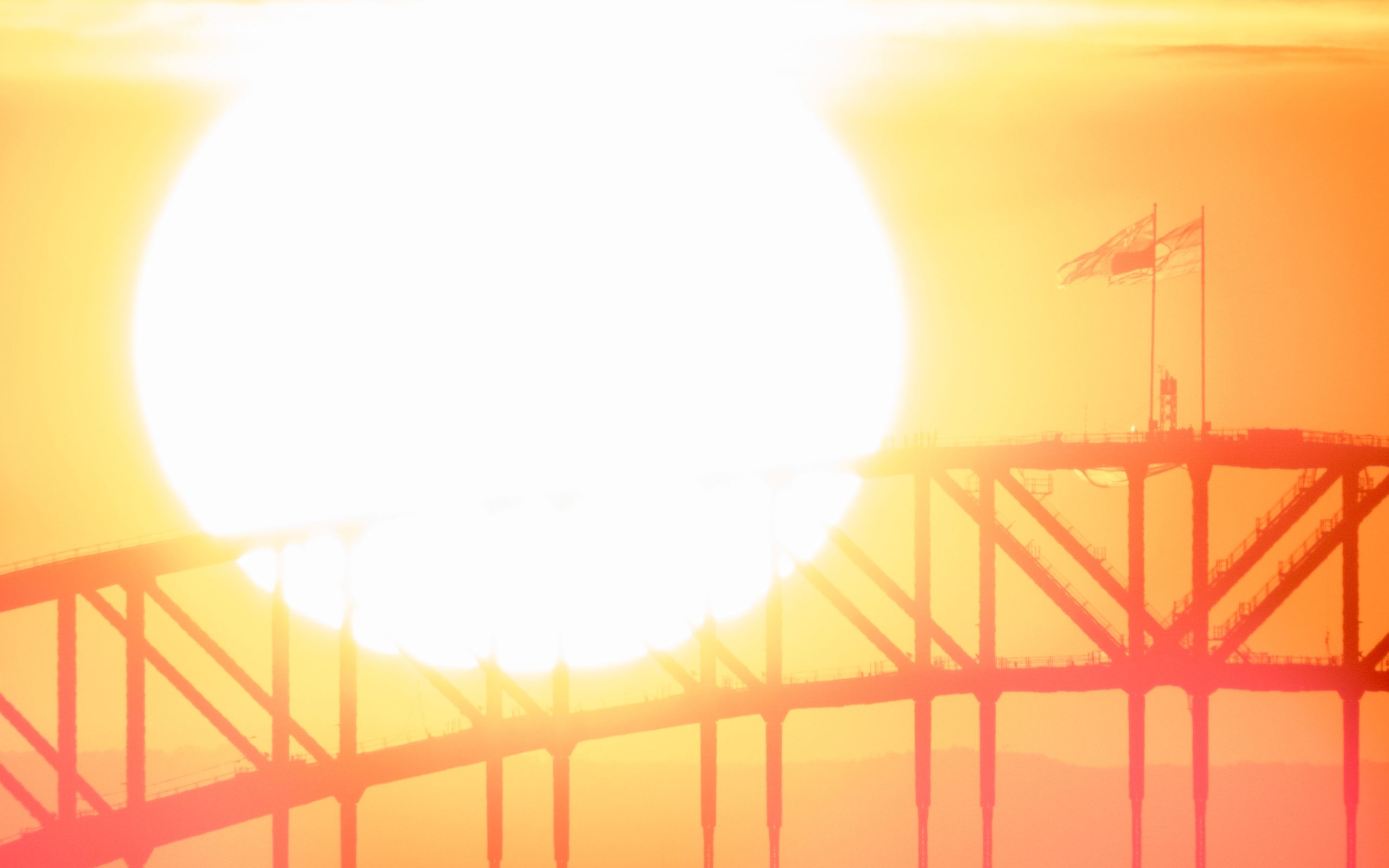 The Australian and Australian Aboriginal Flags fly on the Sydney Harbour Bridge as the sun sets behind the steel structure 2025. Image iStock SCM Jeans