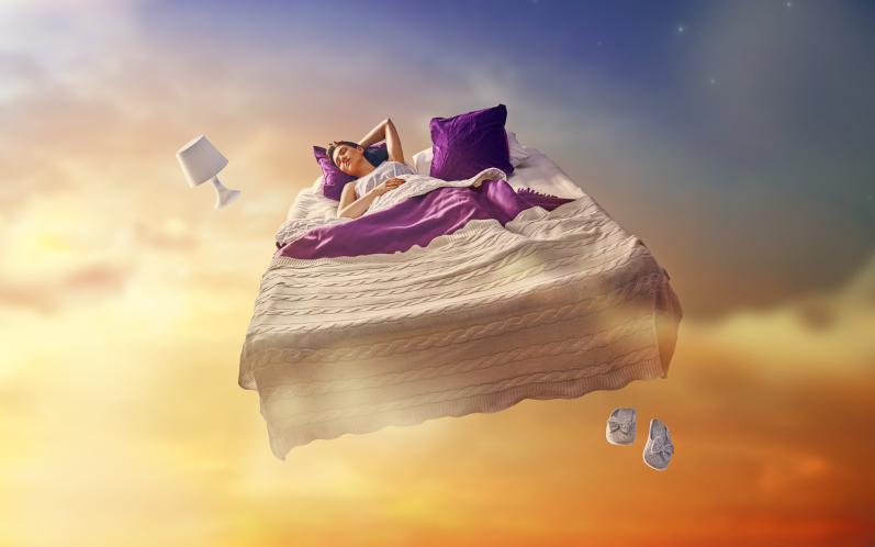 Woman dreaming flying in her bed through sky. Image iStock Choreograph (Konstantin Yuganov)