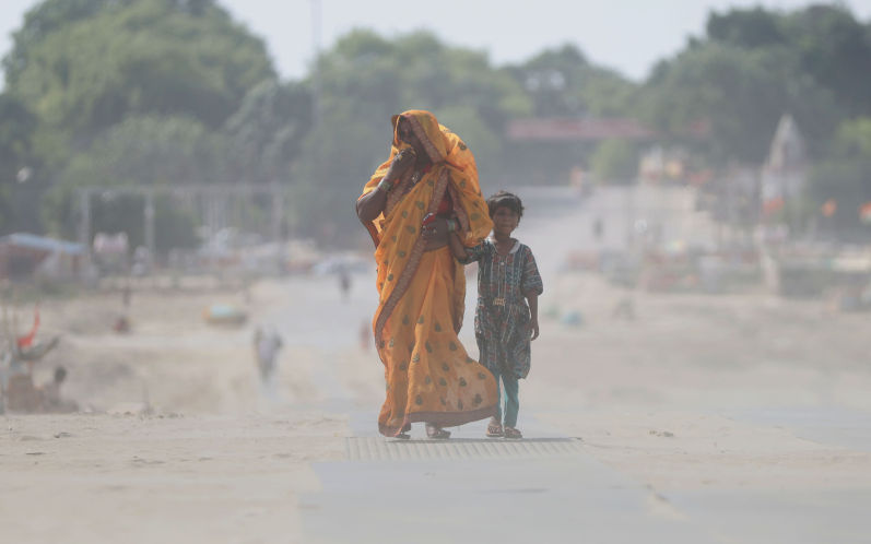 People brave warm dusty wind on a summer day at the banks of Sangam, confluence of river Ganga, Yamuna and mythical Saraswati in Prayagraj, May 2026. Image iStock anil_shakya19