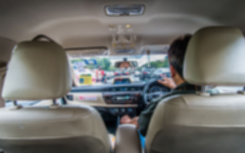 Blurred image of taxi driver from the back seat of the cab. Image iStock Bangkokerz