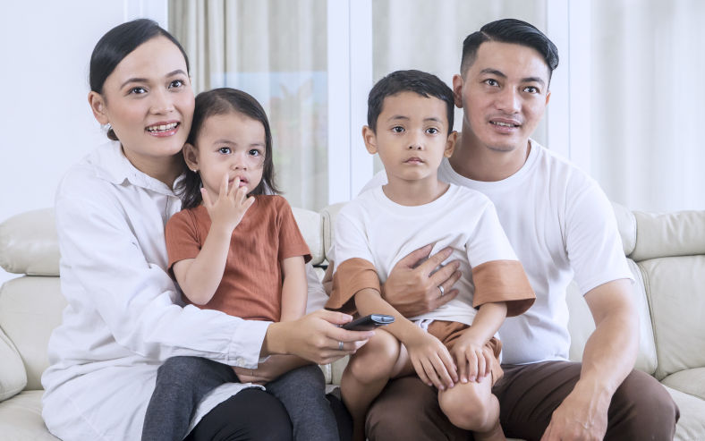 An economically comfortable Indonesian family two parents, two children, at home. Image iStock CreativaImages