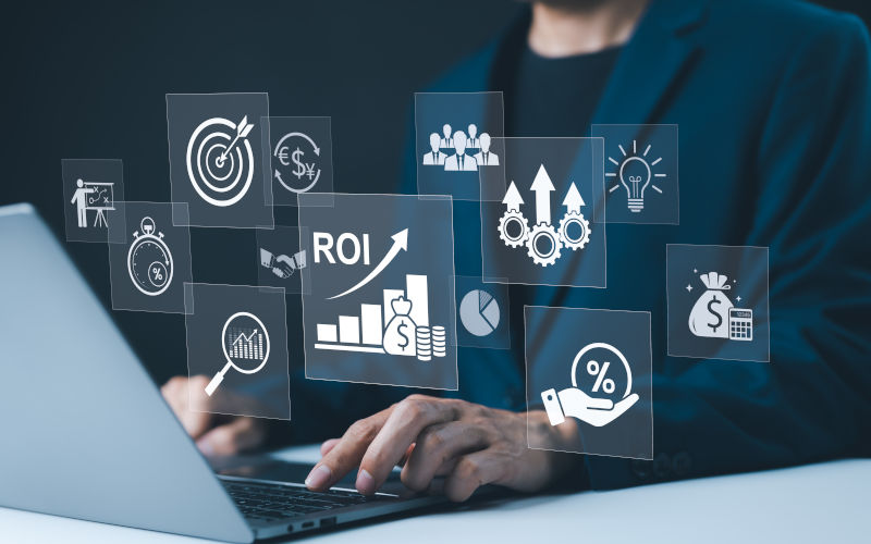 Businessman working on a laptop with various digital icons representing productivity such as ROI, financial strategies, return on investment, and efficiency. marketing plan. Image iStock Supatman