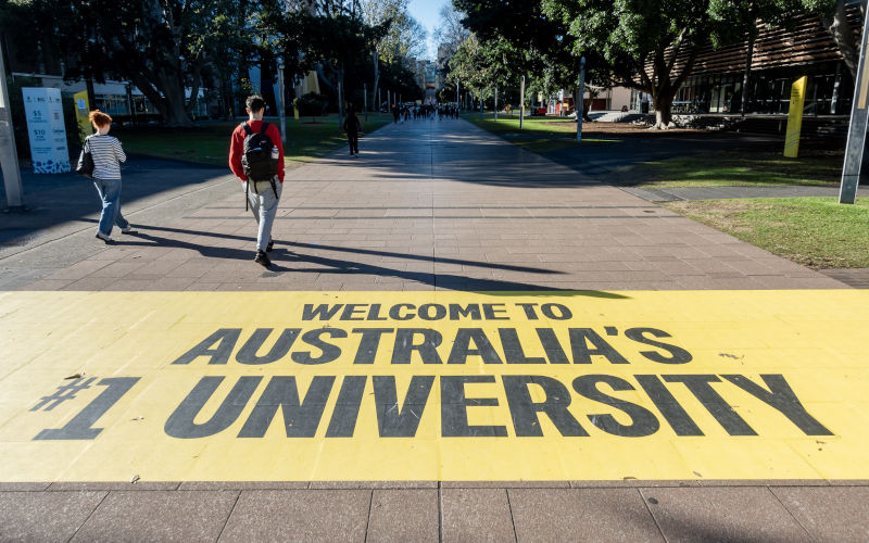 Sydney, Australia Jun 24, 2026 Yellow floor banner along University Mall of the University of New South Wales (UNSW). Celebrating 1st ranking in Australia and 19th globally. Students walking ahead. Image IStock sfeco2