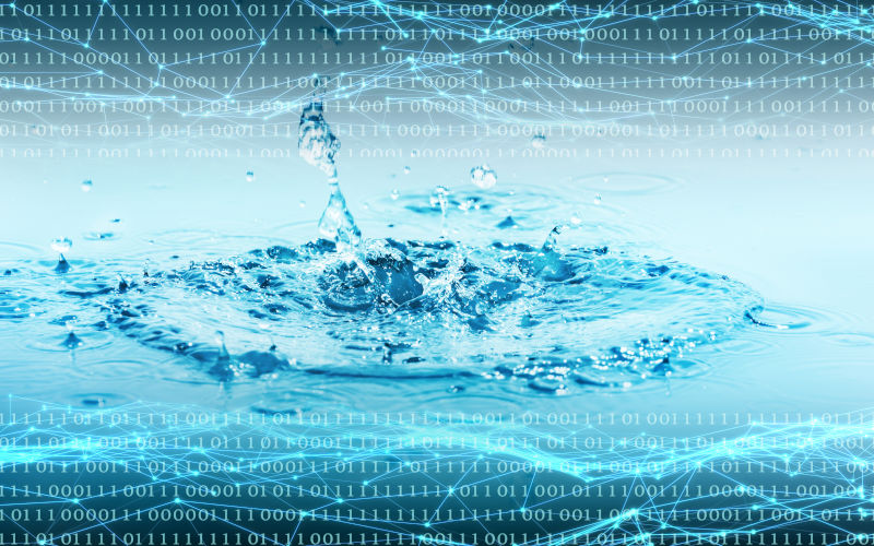Binary code overlay and grid from nodes and lines over a closeup of splashing water drops, illustration of water resources needed for data storage. Image iStock winyuu
