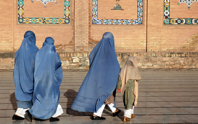 The Great Mosque of Herat (Friday Mosque or Jama Masjid). Three women in burqas and a girl walk at the front of the mosque. The mosque is one of the oldest in Afghanistan. Image iStock Jonathan Wilson
