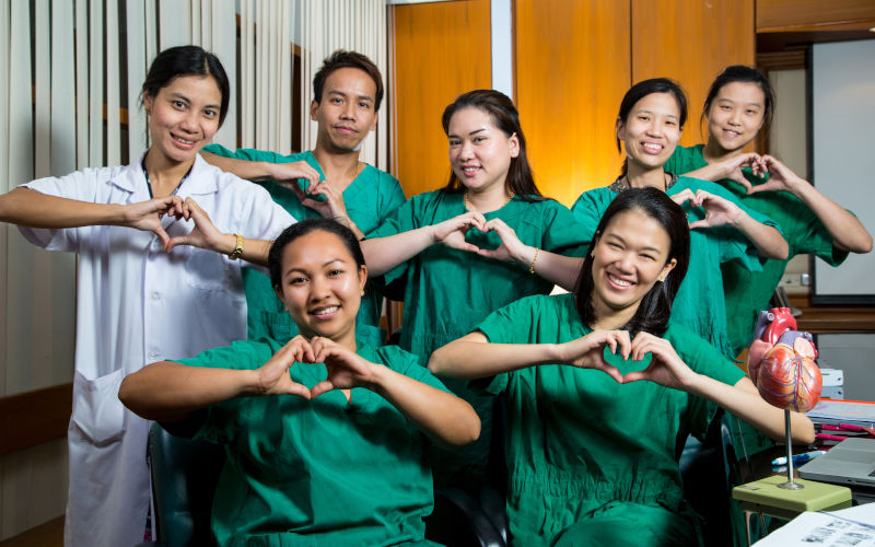 Medical team made up of people from diverse backgrounds make heart sign for the camber. Image iStock ShutterOK