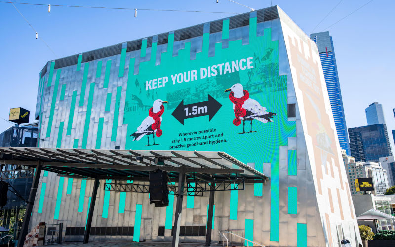 Covid 19 Melbourne advice to socially distance on giant billboard in Federation Square,Melbourne city centre,Victoria,Australia Image Alamy Martin Berry 2021 Image ID 2F51HEE