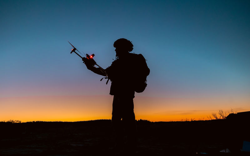Silhouette of soldiers are using drone for scouting during military operation against the backdrop of a sunset. Application of modern technology and AI during war 2025. Image iStock shcherbak volodymyr