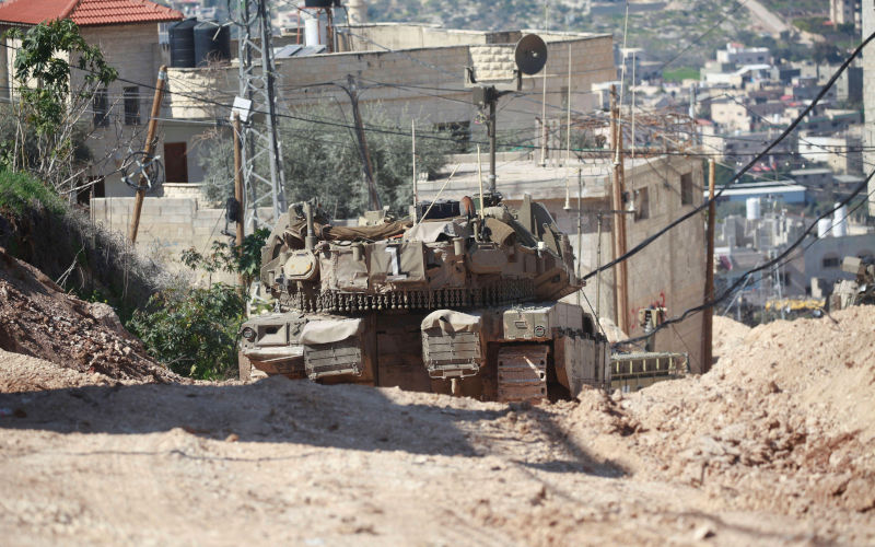 Israeli armored vehicles and bulldozers move through a muddy street during a raid, demolishing buildings and damaging infrastructure at Jenin Refugee Camp in Jenin, West Bank, on February 25, 2025. Image Alamy IMAGO Mohammed Nasser apaimages Image ID 2SY1WD2
