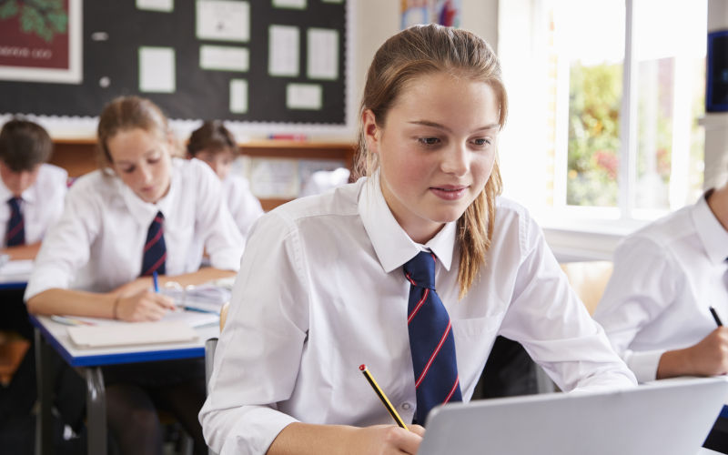 Female pupil wearing uniform using laptop In classroom Image iStock ditmonkeybusinessimages
