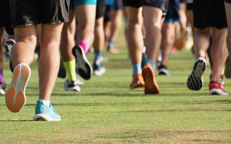 Running athletes run in a run race, running on grass detail on legs, running in the light of morning. ImageiStock Pavel1964