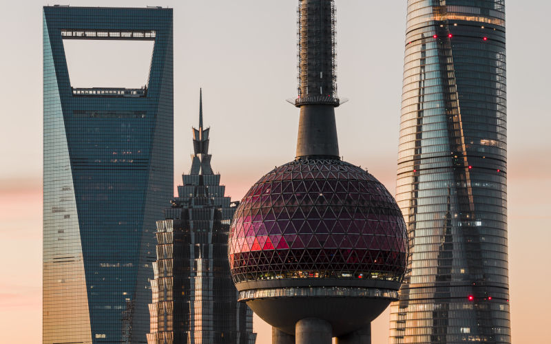 Lujiazui CBD skyscrapers at dawn in closeup aerial view. The majestic Oriental Pearl and Shanghai Tower rise against a soft sunrise, symbolizing a global economic hub. Image iStock chenxiao zhou