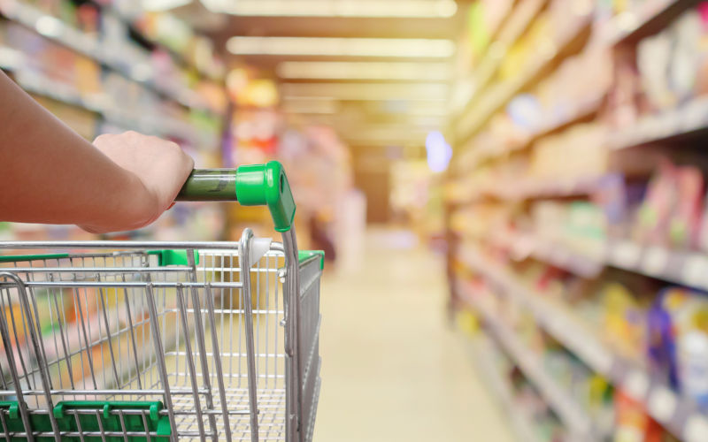 Shopping cart in supermarket aisle with product shelves interior defocused. Image iStock Kwangmoozaa