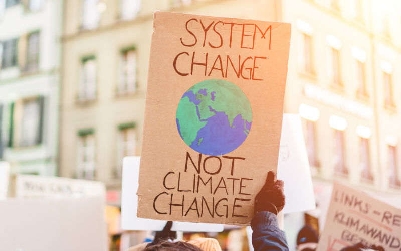 A banner held by people fighting for system change not climate change to reverse and manage global warming. Image iStock DisobeyArt