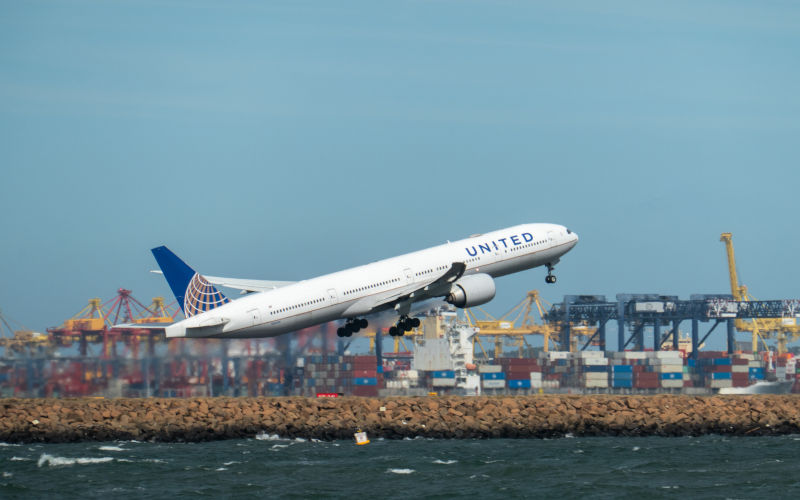 A United Airlines Boeing B777322(ER) plane, registration N2639U, taking off to the south from Sydney KingsfordSmith Airport as flight UA870 to San Francisco. In the background is a container ship docked at the Port Botany Container Terminal. Photo taken 24 January 2025. Image iStock SCM Jeans