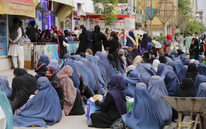 A number of poor Afghan women sitting in front of a bakery in capital Kabul to receive a piece of bread to feed their children. 2022 Image iStock CreditSohrab Omar