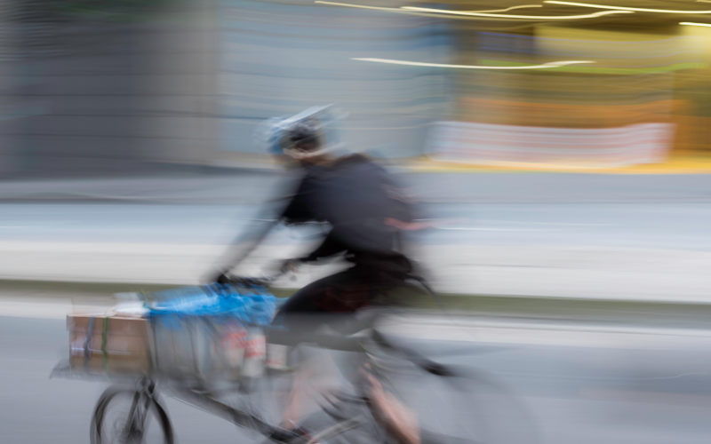 A blurred image of a speeding bicycle courier working on the streets of Sydney, Australia. Image Alamy Sydney Photographer. Image ID W2NN2A