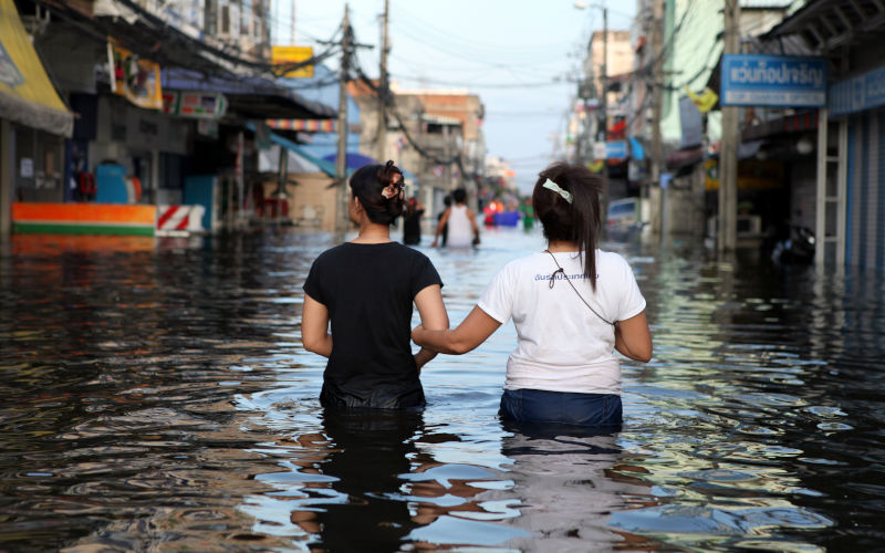Bangkok, Thailand Two friends lock arms for comfort as they walk down a flooded street of Rangsit in Pathum Thani province, returning home to a badly effected suburb, Northeast of Bangkok. ImageiStock F����lixLaframboise