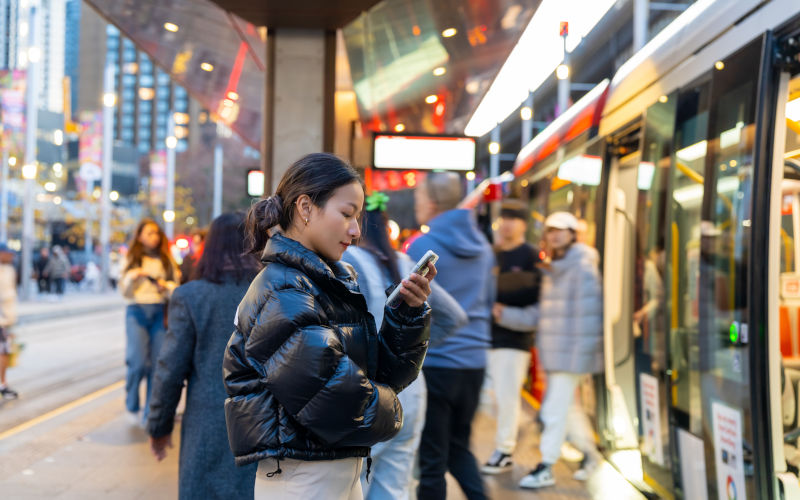 Asian businesswoman using mobile phone at train station. Image iStock CandyRetriever